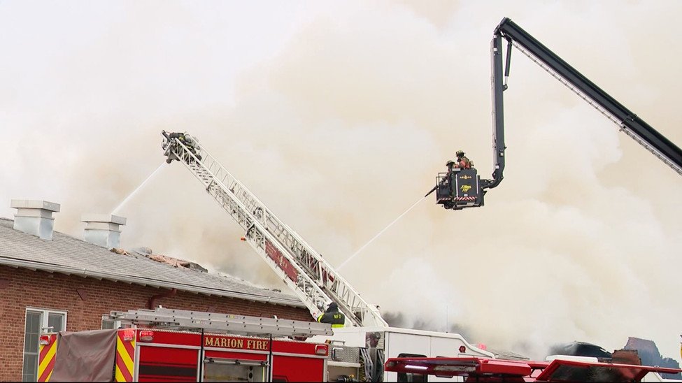 Elevated master stream operations deployed to control heavy smoke and fire conditions above the roofline.