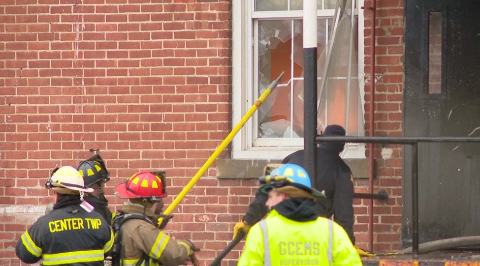 Fire crews are ventilating and accessing affected brick structures during overhaul operations.