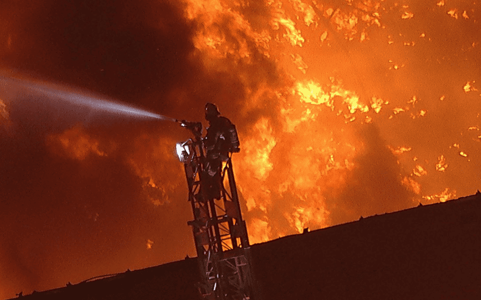 firefighter works to control the industrial furniture warehouse fire